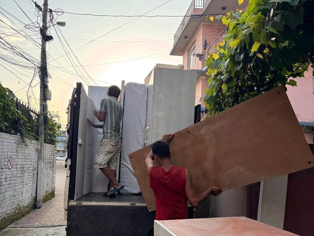 Worker carefully passing furniture panel onto truck