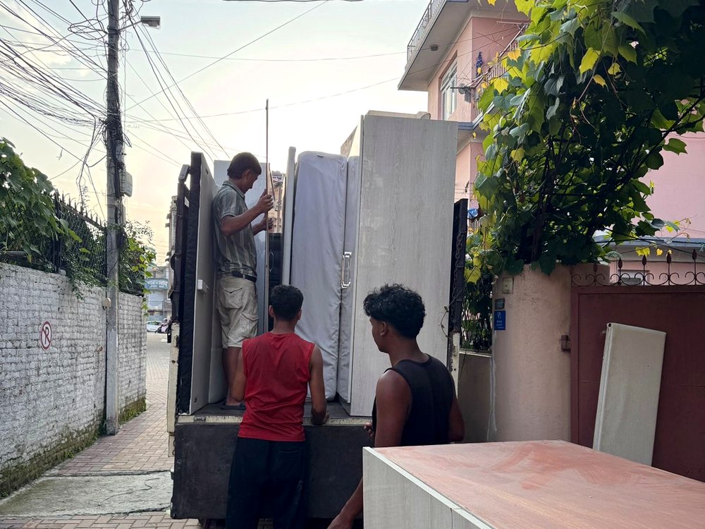 Workers loading mattresses onto truck in alley